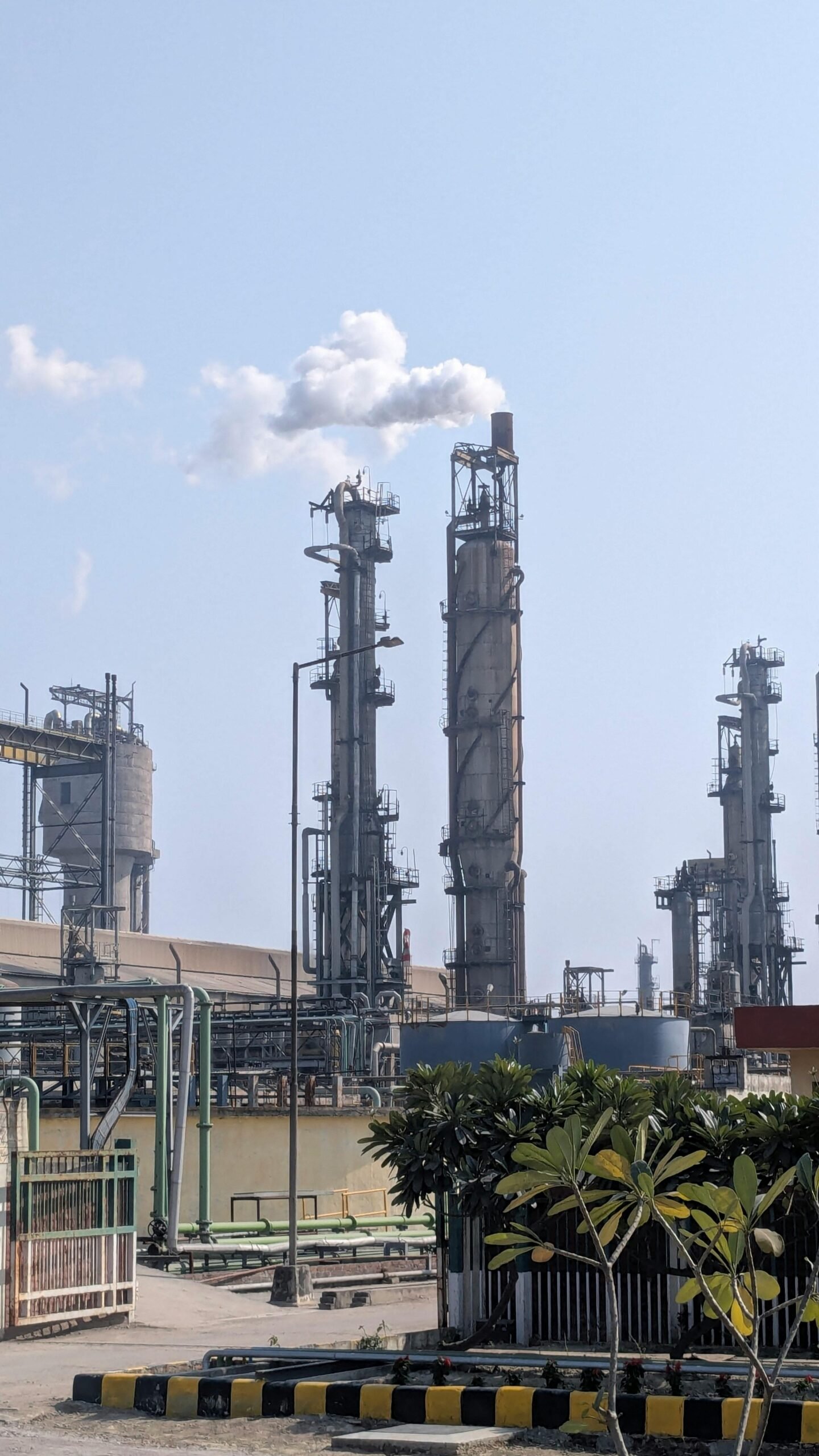 A detailed view of a chemical plant's tall chimneys and industrial structures against a clear sky.